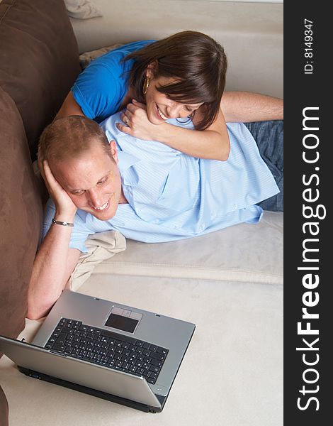 Young couple on the couch at home looking at the laptop!. Young couple on the couch at home looking at the laptop!