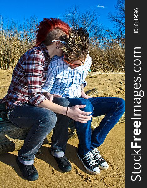 Two young women sitting on a log at the beach