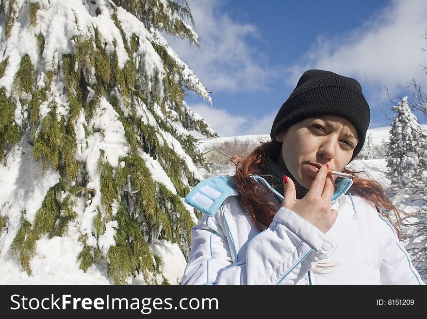 Young woman at a snow park smoking a cigarette. Young woman at a snow park smoking a cigarette