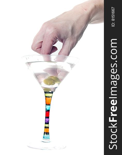 A female hand dips into martini to pluck out two olives on a toothpick. A female hand dips into martini to pluck out two olives on a toothpick