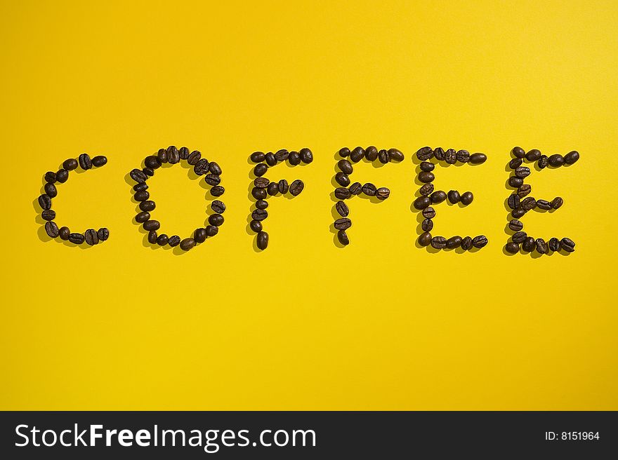 Coffee written with beans on yellow background.