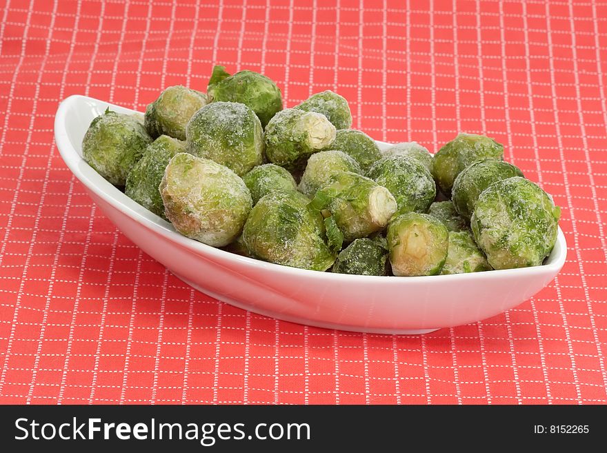 Frozen Brussels sprouts in a bowl on red background