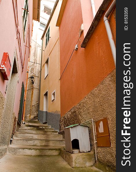 Dog house on in a narrow alley with stairs, Manarola, Italy. Lady in window many stories above, postbox across. Dog house on in a narrow alley with stairs, Manarola, Italy. Lady in window many stories above, postbox across.