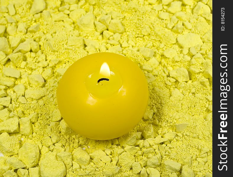 Yellow candle with fire on crushed chalk background