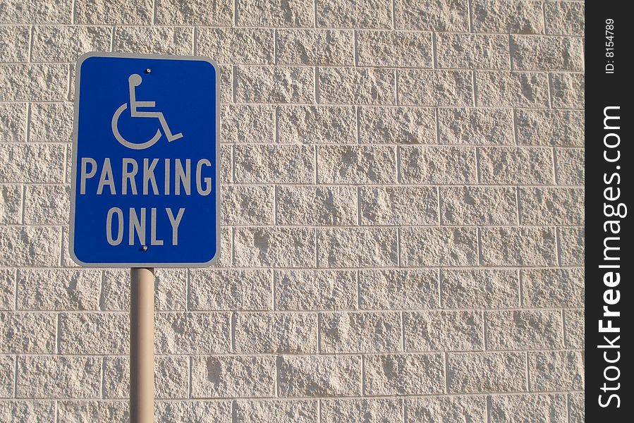 Blue handicap parking sign with a white textured concrete block background that can be used for copy space. Blue handicap parking sign with a white textured concrete block background that can be used for copy space.