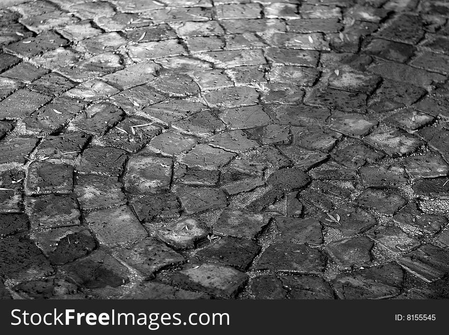 Black and white image of paving laid with broken bricks. There is a circular pattern visible. Black and white image of paving laid with broken bricks. There is a circular pattern visible