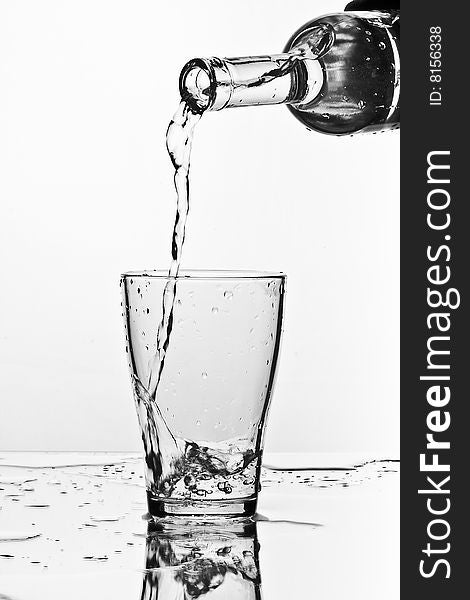 Glass of pouring water with reflection (white background)