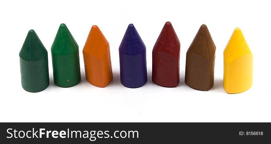 Seven wax crayons several colors on white background