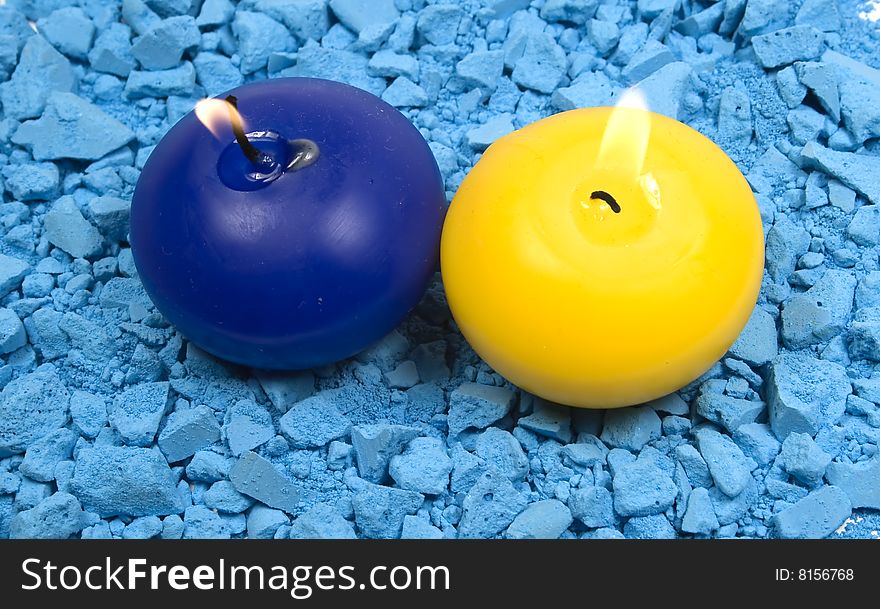 Two candles with fire on crushed chalk background
