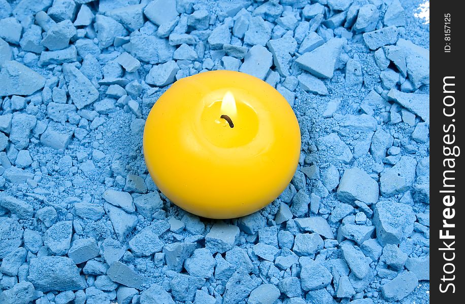 Yellow candle with fire on crushed chalk background