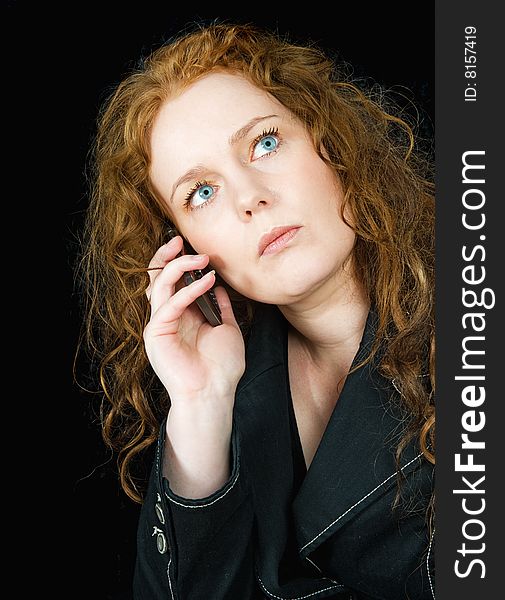 Beautiful girl with red hair speaking in mobile phone, seen against black background. Beautiful girl with red hair speaking in mobile phone, seen against black background
