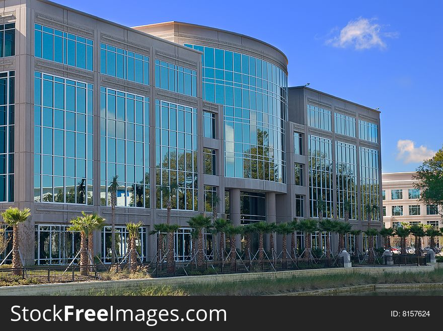 Office building with reflected trees and blue skies. Office building with reflected trees and blue skies.