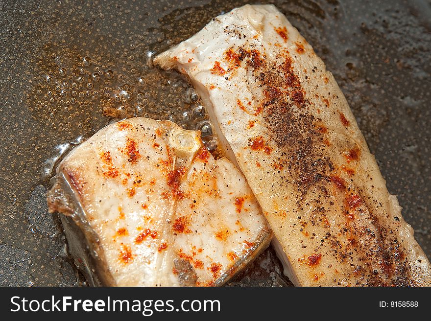 Fried fish with spices in the cooking pan