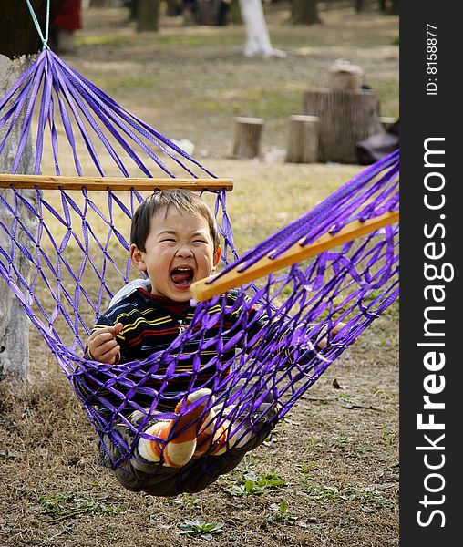 A picture of a little chinese boy laughing and having great fun in hammock. A picture of a little chinese boy laughing and having great fun in hammock