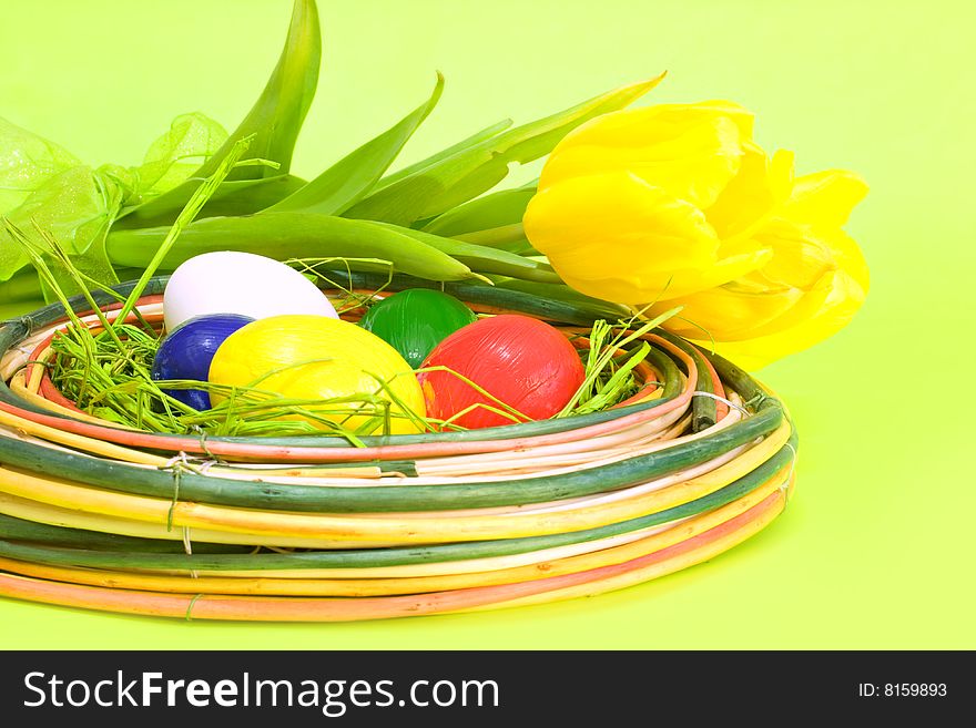 Colored Easter eggs with yellow tulips on green background