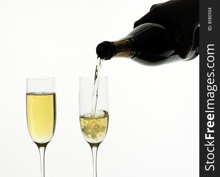 Champagne being poured into a flute, isolated on a white background.