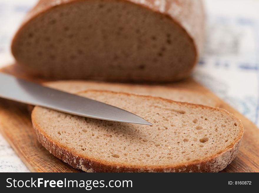 Pieces of bread on breadboard with knife. Close-up