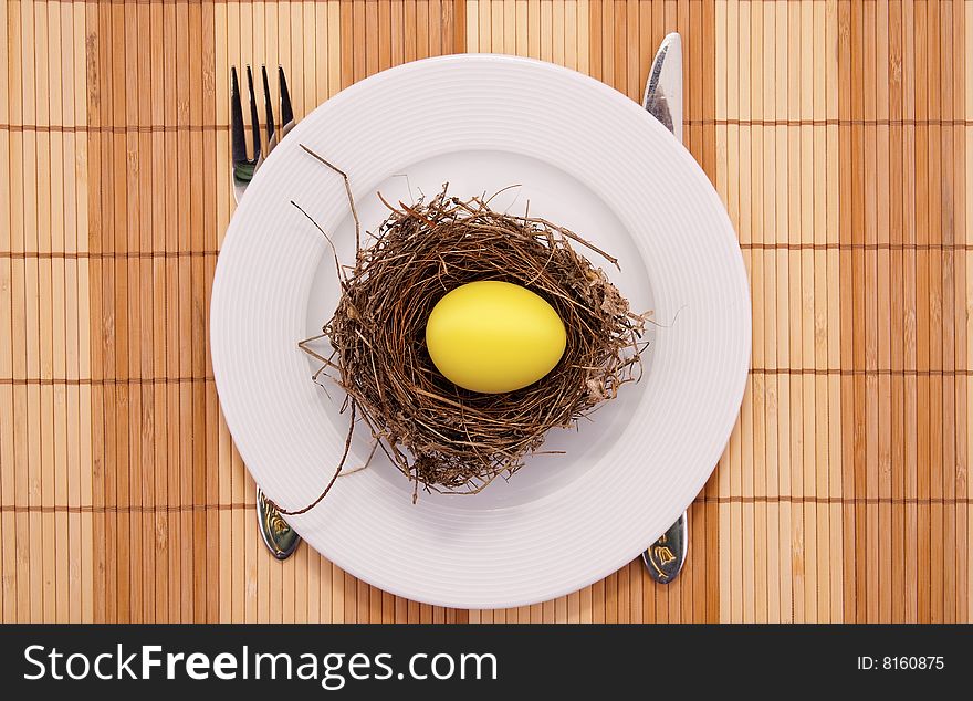 Gold egg in a nest served on a plate. Close-up