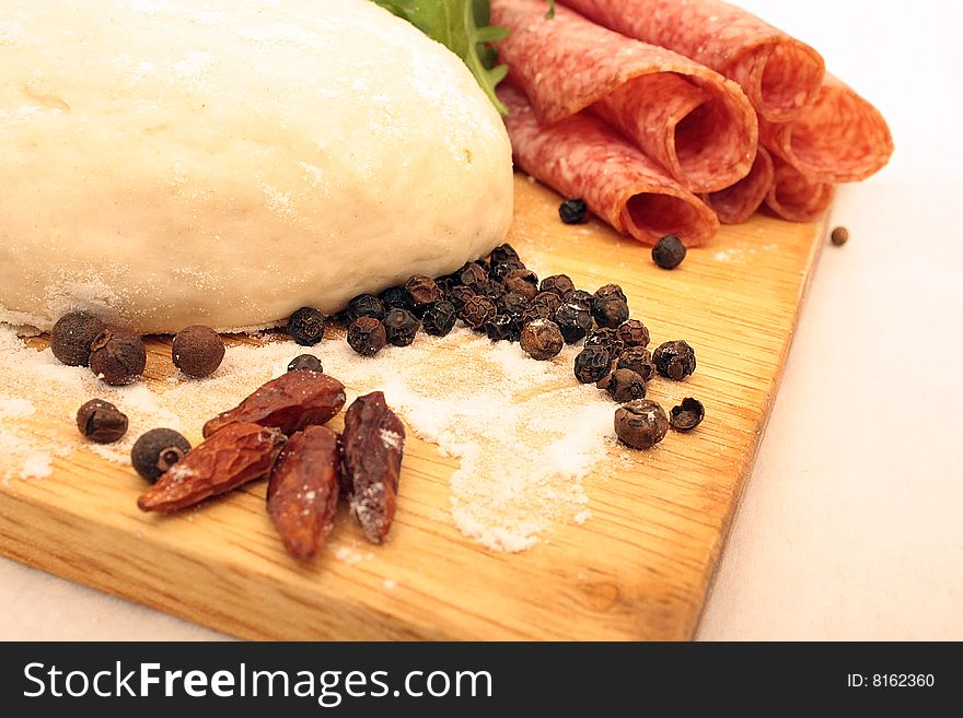 Pizza dough, pepper, salami and rukola on the board. Pizza dough, pepper, salami and rukola on the board.