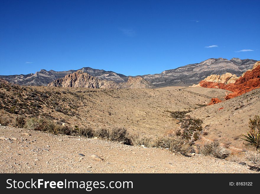 Brown and red desert landscape under a vivid blue sky