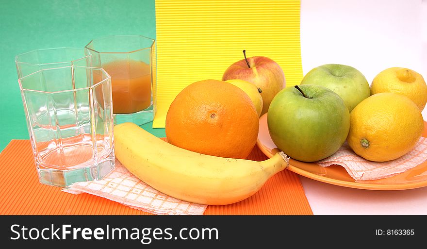 Fresh seasonal fruit, apples, bananas, orange and glass fruit juice on reflective underground