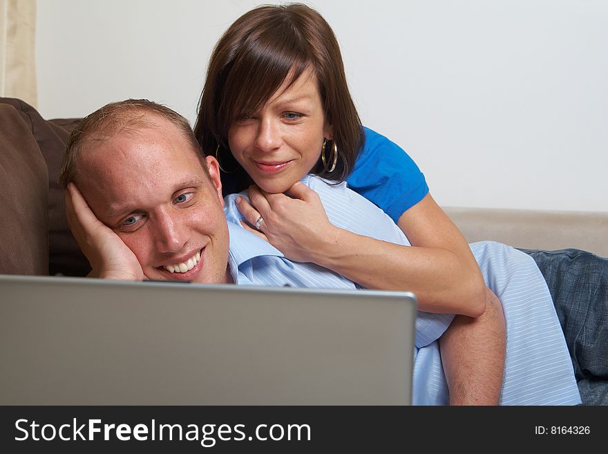 Young couple on the couch at home looking at the laptop!. Young couple on the couch at home looking at the laptop!