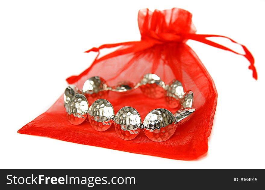 An image of a metal bracelet  with a red bag over white background