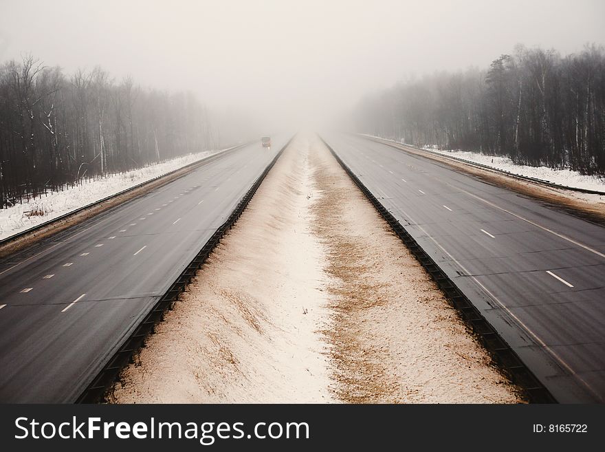 Snowy highway in the dark foggy forest