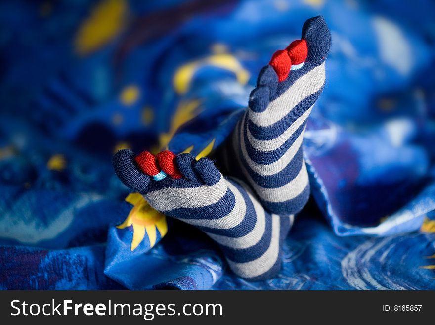 Stock photo: an image of little feet in striped socks on a bed