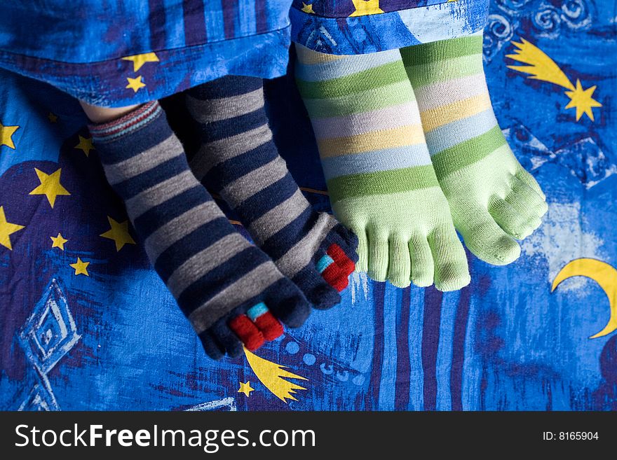 Stock photo: an image of two pairs of funny feet in striped socks. Stock photo: an image of two pairs of funny feet in striped socks