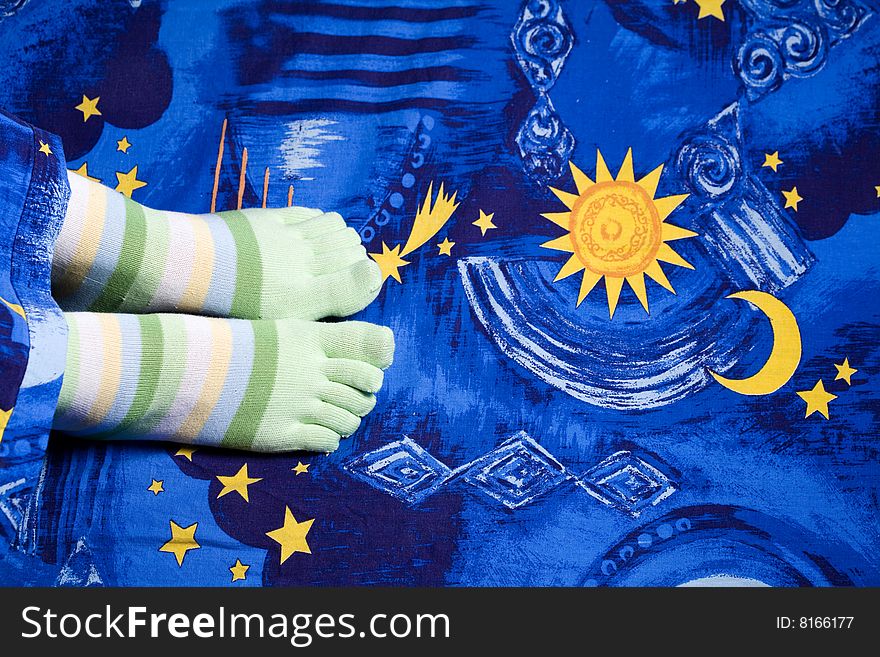 Stock photo: an image of funny feet in green striped socks on sheet. Stock photo: an image of funny feet in green striped socks on sheet
