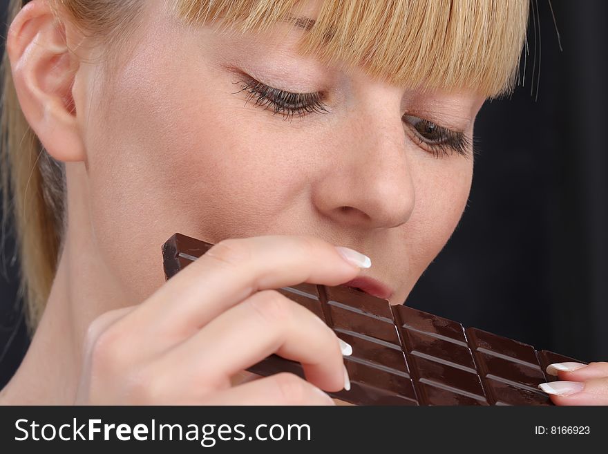 Blond girl eat dark chocolate close up. Blond girl eat dark chocolate close up