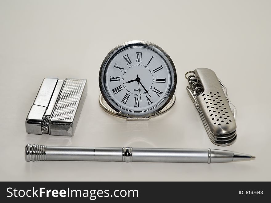 A close-up of the men's silvery accessories: watch, knife, lighter, pen. A close-up of the men's silvery accessories: watch, knife, lighter, pen.