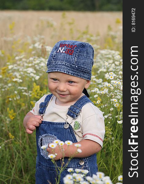 The little boy works as photomodel on a meadow with camomiles. The little boy works as photomodel on a meadow with camomiles