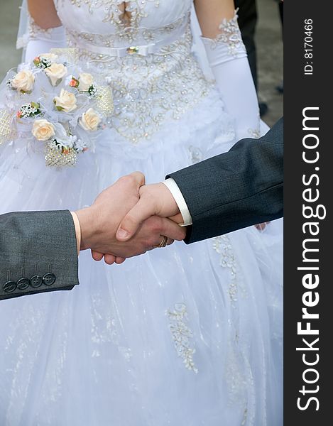 Man's hand shake against a bridal outfit - a congratulation on a holiday. Man's hand shake against a bridal outfit - a congratulation on a holiday.