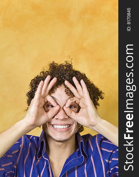 Young man with hand over eyes, looking through fingers. Young man with hand over eyes, looking through fingers