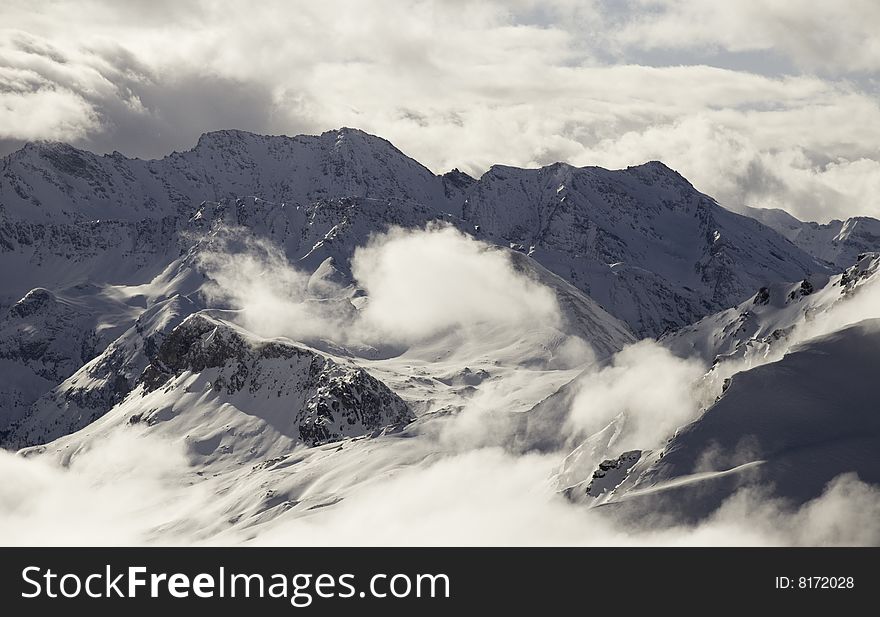 Snow covered french alpine paeks with low cloud. Snow covered french alpine paeks with low cloud