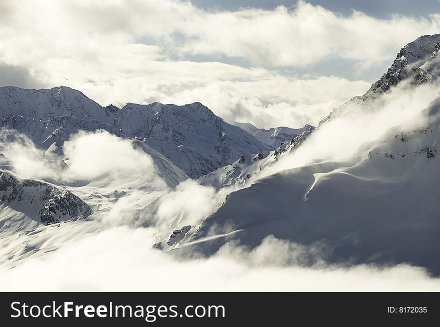 Snow covered mountain peaks at altitude in the French Alps including Mont Cenis surrounded by low cloud