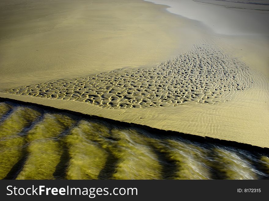 Shallow spring water flowing over sand on a beach. Shallow spring water flowing over sand on a beach