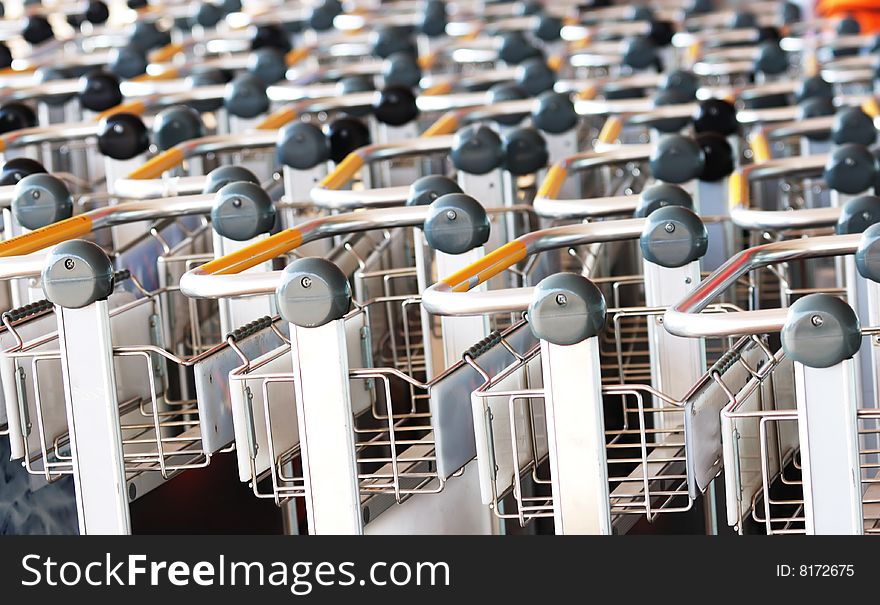 A closeup view of the handles of several rows of supermarket shopping carts. A closeup view of the handles of several rows of supermarket shopping carts