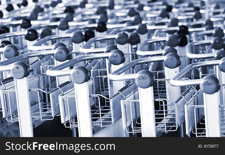 A closeup view of the handles of several rows of supermarket shopping carts. A closeup view of the handles of several rows of supermarket shopping carts