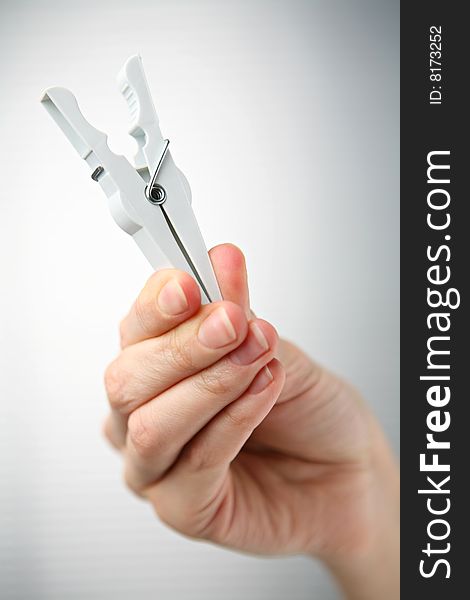 White clothespin in hand on grey background