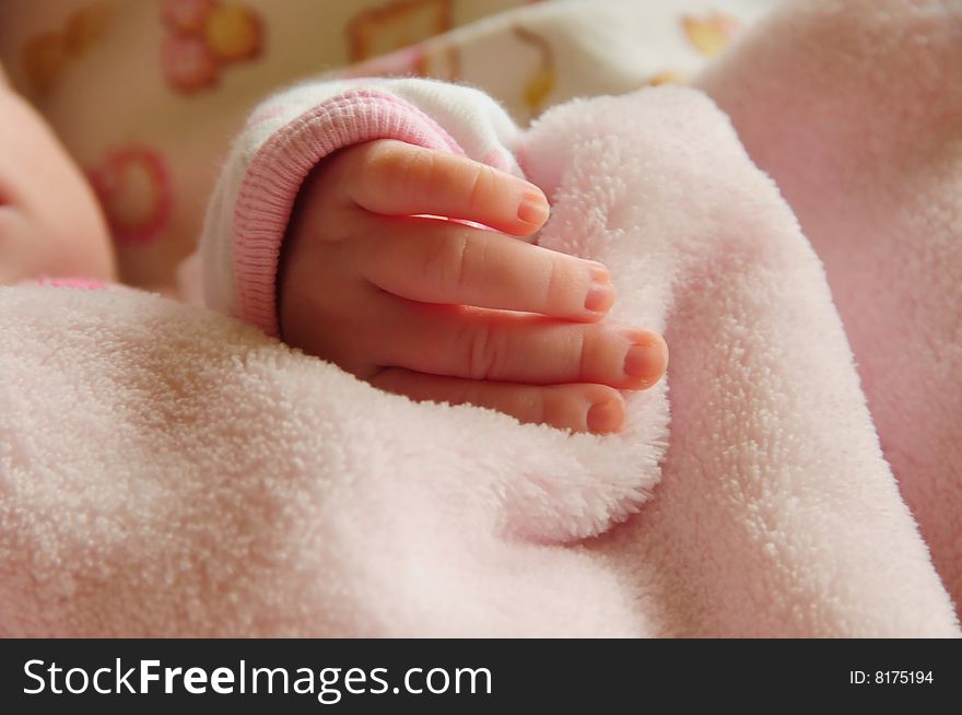 Delicate new baby's fingers on a pink blanket