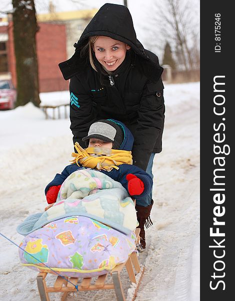 Mom pushes child sledging in winter. Mom pushes child sledging in winter