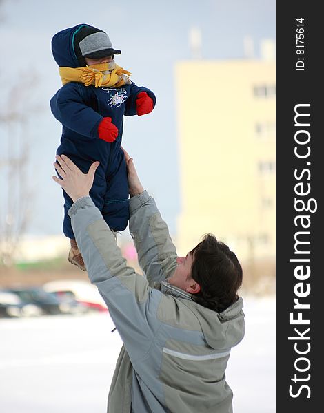 Father toss up the child to on the snow in winter. Father toss up the child to on the snow in winter