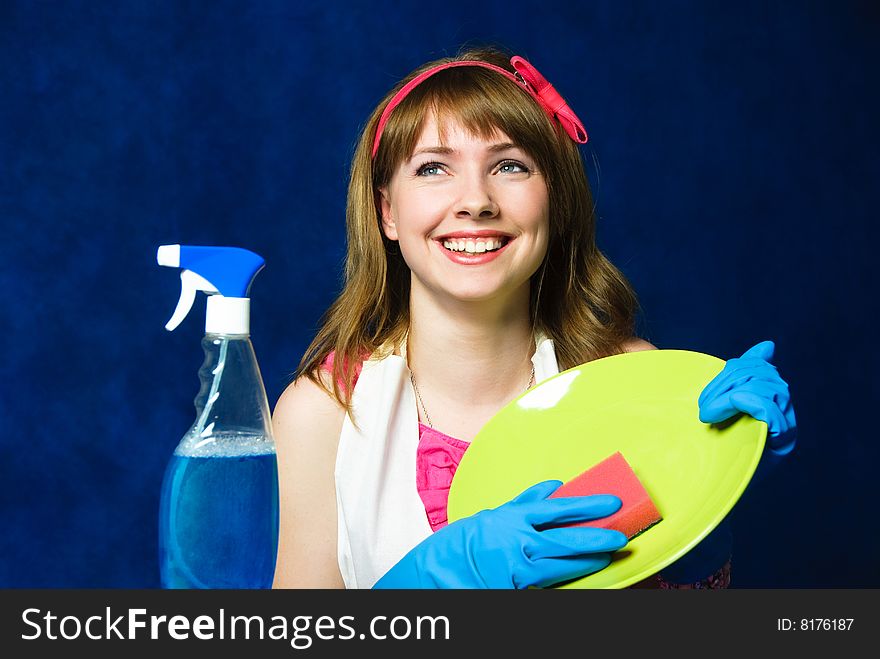 Beautiful young housewife washing the dishes against blue background