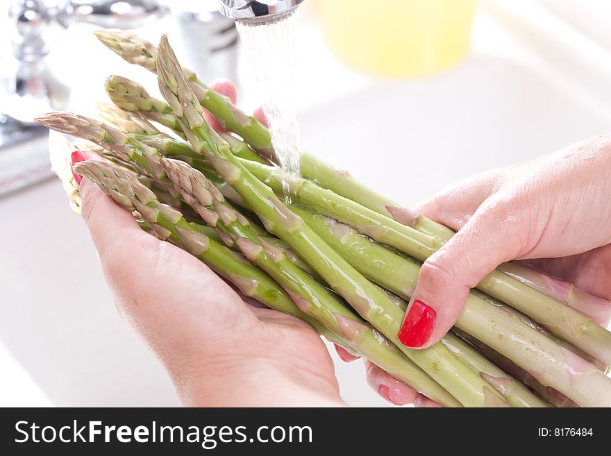 Woman Washing Asparagus in the Kitchen Sink.