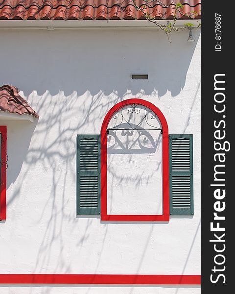 A false window in red with green shutters on stucco. A false window in red with green shutters on stucco