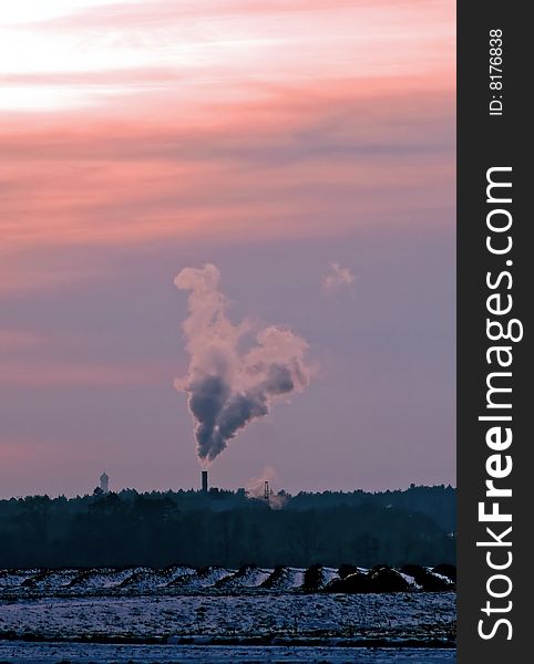 A smoking chimney in the light of a sunset. A smoking chimney in the light of a sunset