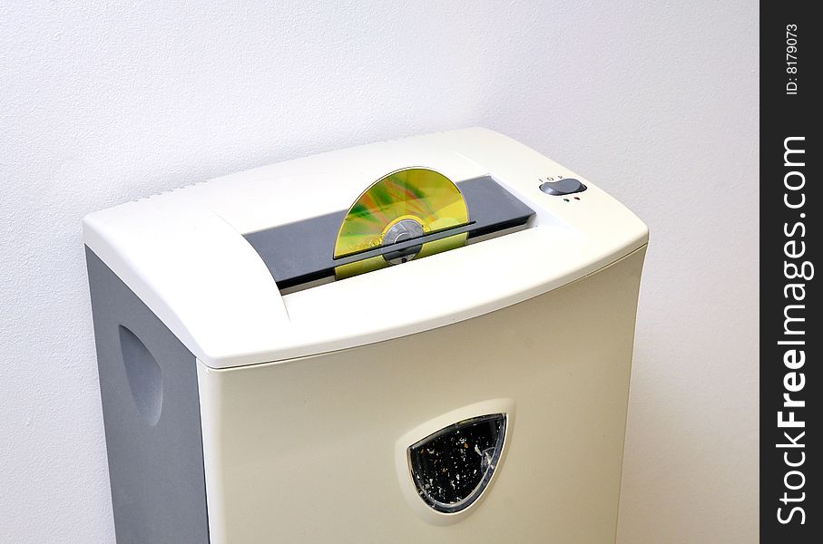 Thre quarte view of CD shredder with gold disk inserted on a white wall background